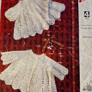 Puede incluir: Un patrón de ganchillo vintage para un suéter de bebé. El patrón es para un hilo de 4 cabos e incluye tres tallas para bebés de 18 a 20 pulgadas. El patrón se llama "Emma" y es el número 8427.