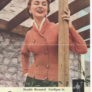 May include: A woman wearing a double-breasted cardigan in a peach colour. The cardigan is knitted with a ribbed pattern and has a collar. The woman is smiling and has her hand on a wooden post. The text on the image reads "Double Breasted Cardigan in Scotch Double Knitting" and includes sizing information for bust and yarn weight.