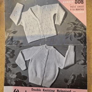 Puede incluir: Patrón de tejido vintage con dos diseños de cárdigan para bebé. El cárdigan superior es un estilo abotonado con un patrón de puntos texturizados. El cárdigan inferior es un diseño clásico de cuello redondo. El patrón es de "Wendywool" e incluye información de tallas.