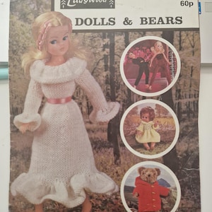 May include: A vintage "Ladywood" pattern booklet titled "Dolls & Bears." The cover shows a doll in a white knitted dress with a pink belt. The booklet includes images of dolls and a teddy bear in a red coat. The price is 60p.