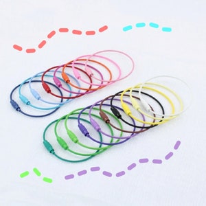 May include: A set of 18 colorful key rings made of metal wire. The key rings are arranged in a semi-circle, with the colors ranging from pink to green.