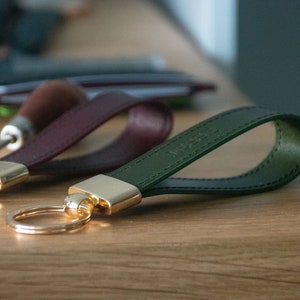 May include: Two leather keychains with gold key rings. One keychain is burgundy and the other is dark green.