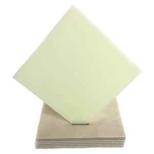 May include: A pale yellow square piece of material on a wooden base. The material is translucent and appears to be a type of plastic or acrylic.