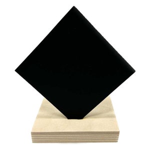 May include: A black diamond-shaped piece of material on a wooden base. The material is smooth and appears to be a type of plastic or acrylic.