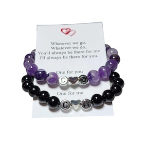 May include: Two bracelets, one with purple amethyst beads and one with black beads. Both bracelets have silver charms with the letters C and M and a heart charm. The card reads: "Wherever we go, Whatever we do, You'll always be there for me I'll always be there for you. One for you One for me"