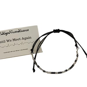 Puede incluir: Un brazalete de cuerda negra con cuentas plateadas que deletrea "Until We Meet Again" en código Morse. El brazalete viene con una tarjeta que dice "A Hug From Heaven" e incluye el código Morse del mensaje.