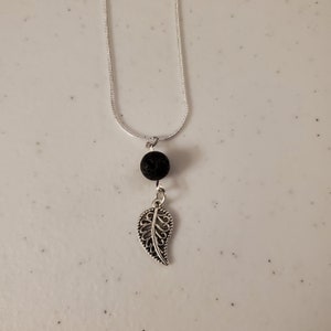 May include: A silver chain necklace with a black lava rock bead and a silver leaf pendant.