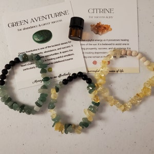 Könnte beinhalten: Zwei Armbänder aus grünem Aventurin und Citrin. Die Armbänder liegen auf einer weißen Oberfläche mit Karten, auf denen "Grüner Aventurin für Fülle und beruflichen Erfolg" und "Citrin für Erfolg und Freude" steht.