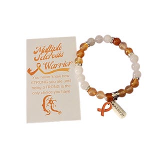 May include: Orange, white and silver beaded bracelet with a charm that says "Warrior". The bracelet is accompanied by a card that reads "Multiple Sclerosis Warrior" and includes a quote about strength.
