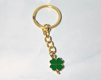 May include: A gold-colored keychain with a green four-leaf clover charm.
