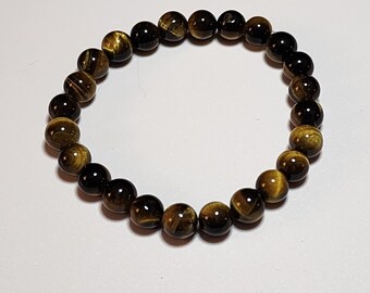 May include: A brown and gold tiger's eye beaded bracelet. The bracelet is made of round beads and is approximately 7 inches in length.