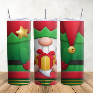 May include: A set of three Christmas-themed tumblers featuring a gnome design. The tumblers have a red and green color scheme, with a gold star, a gift box, and a bell. The tumblers are cylindrical and have a straw.