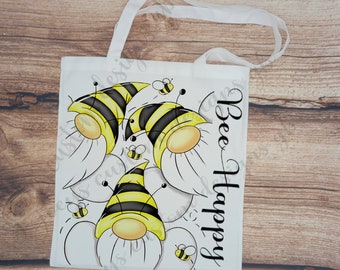 May include: White tote bag with a bee-themed design. The bag features multiple cartoon bees with yellow and black stripes and the text "Bee Happy".