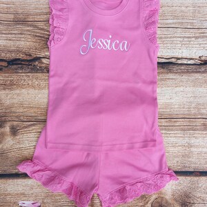 May include: Pink sleeveless top and shorts set with white eyelet trim and the name "Jessica" embroidered on the front of the top.