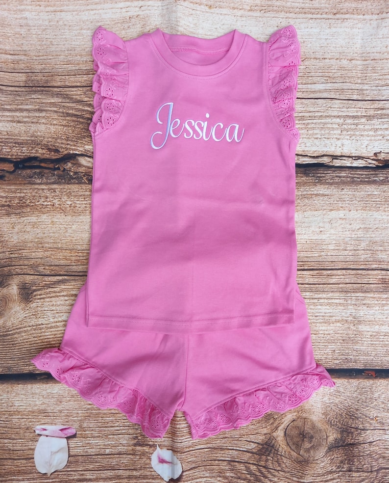 May include: Pink sleeveless top and shorts set with white eyelet trim and the name "Jessica" embroidered on the front of the top.