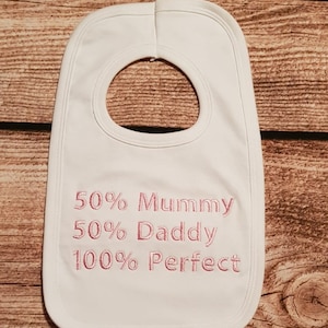 Puede incluir: Babero blanco para bebé con bordado rosa que dice "50% Mamá 50% Papá 100% Perfecto"