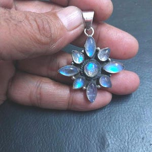 May include: A silver pendant with a starburst design featuring eight iridescent moonstone gems.