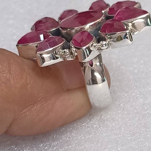 May include: A silver ring with a cluster of pink ruby stones set in a flower shape.