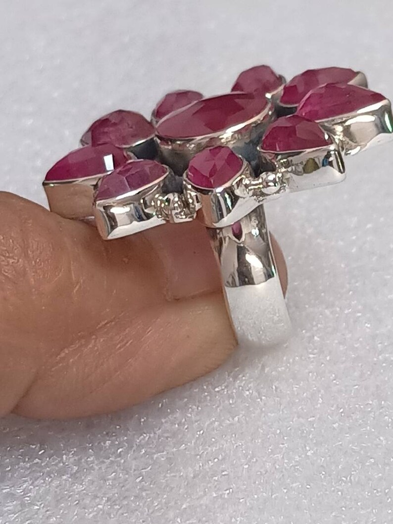 May include: A silver ring with a cluster of pink ruby stones set in a flower shape.
