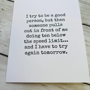 May include: A white greeting card with black text that reads: "I try to be a good person, but then someone pulls out in front of me doing ten below the speed limit... and I have to try again tomorrow."