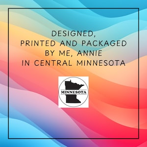 May include: A colorful background with a gradient of blue, yellow, orange, and red. The text reads "DESIGNED, PRINTED AND PACKAGED BY ME, ANNIE IN CENTRAL MINNESOTA." A black and white Minnesota state outline is in a circle.