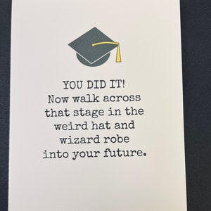 May include: A graduation card with a black graduation cap and the text "YOU DID IT! Now walk across that stage in the weird hat and wizard robe into your future."