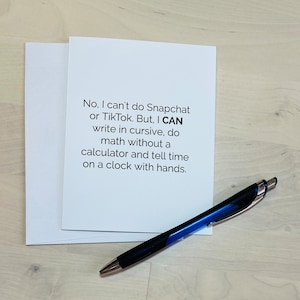 May include: A white greeting card with a matching envelope, and a black and blue pen. The card has the text: "No, I can't do Snapchat or TikTok. But, I CAN write in cursive, do math without a calculator and tell time on a clock with hands."