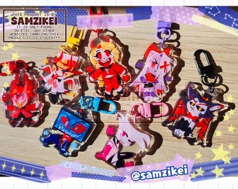 May include: A collection of six acrylic character keychains featuring vibrant, stylised illustrations of animated figures with red, white, blue, and black colour schemes. Each keychain includes a colourful plastic clasp for attachment.
