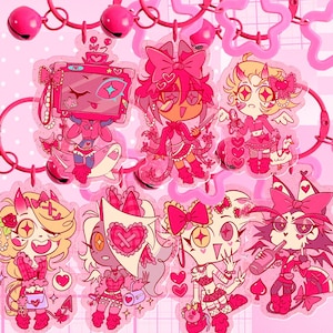 May include: A collection of pink cartoon character charms with various designs, including bows, hearts, and stars. The charms are connected by pink chains and decorative elements, creating a playful and whimsical aesthetic.