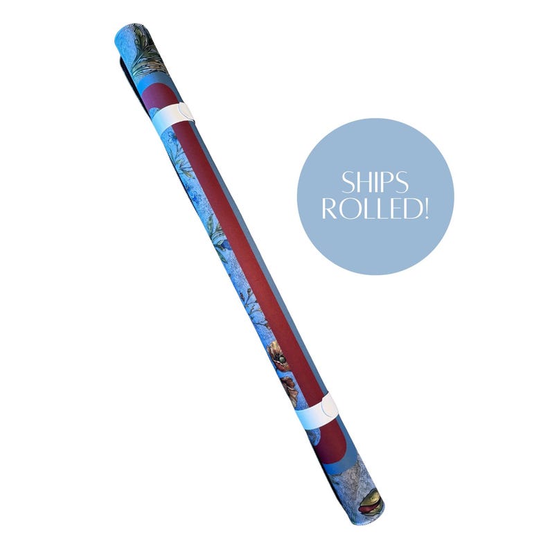 May include: A long, cylindrical rolled item featuring a blue background with a floral pattern and a prominent dark red vertical stripe. Two white bands secure the roll. A light blue circular graphic contains the white text SHIPS ROLLED!