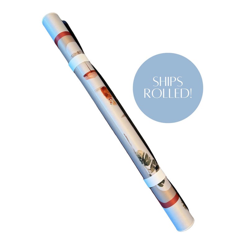 May include: A cylindrical poster tube featuring a light-colored surface with a botanical print of green leaves and orange accents. The tube is secured with two white bands and includes a light blue circular graphic with the text SHIPS ROLLED!