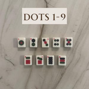 May include: A set of nine white Mahjong tiles, each displaying a number of dots from one to nine. The dots are red and green, arranged in various patterns. The text "DOTS 1-9" is at the top.