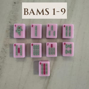 May include: Nine pink Mahjong tiles with green and red markings, numbered 1 through 9. The top of the image reads "BAMS 1-9". The tiles are arranged in a grid, showcasing the different symbols and numbers.