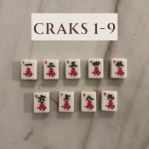 May include: A set of nine white Mahjong tiles, each with a red and black Chinese character and number. The tiles are arranged in two rows. The text "CRAKS 1-9" is displayed above the tiles.