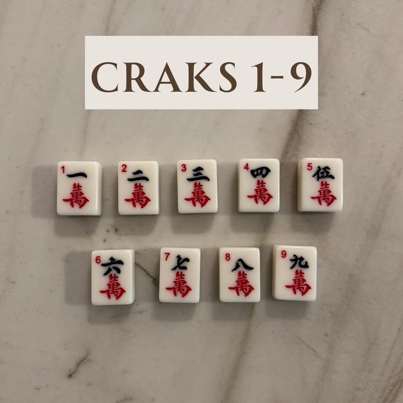 May include: A set of nine white Mahjong tiles, each with a red and black Chinese character and number. The tiles are arranged in two rows. The text "CRAKS 1-9" is displayed above the tiles.