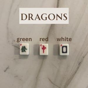 May include: Three white Mahjong tiles with green, red, and black symbols. The word "DRAGONS" is above the tiles. The tiles are labeled "green", "red", and "white".
