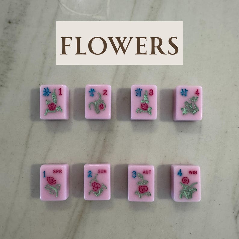 May include: Pink Mahjong tiles with floral designs and numbers 1-4, plus SPR, SUM, AUT, and WIN. The word "FLOWERS" is displayed above the tiles in brown letters. The tiles are arranged in two rows of four.
