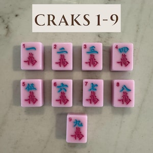 May include: Nine pink Mahjong tiles with Chinese characters and numbers 1-9. The tiles have teal and red accents. The text "CRAKS 1-9" is at the top of the image.