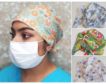 May include: A collection of four colorful surgical scrub caps with different patterns. The caps are made of fabric and have ties to secure them in place. The patterns include floral, butterflies, tropical birds, and lavender.