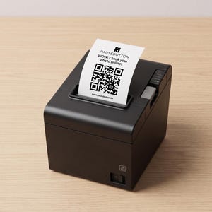 Puede incluir: Una impresora térmica negra con un recibo blanco que muestra un código QR y el texto "PAUSEBUTTON WOW! Check your photo online!". La impresora está sobre una superficie de madera clara.