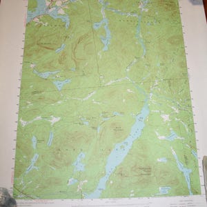 May include: A vintage topographic map of the Long Lake, NY area. The map shows the location of various lakes, rivers, mountains, and other geographical features. The map is printed on a white background with green and blue lines and text.