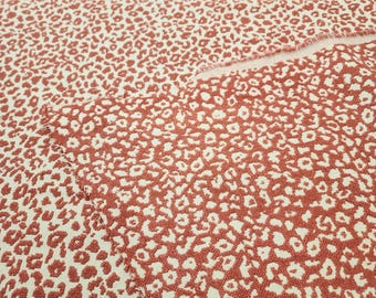 May include: Close-up of a fabric with a white background and a red leopard print pattern.