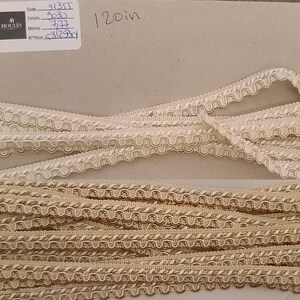 May include: A close-up of beige and cream colored trim with a scalloped edge. The trim is arranged in multiple layers. A label with the text "Code: 3135T, Colors: 3030, Metres: 37.74, N°Price: 512.90y" and "120in" is visible in the top right corner of the image.