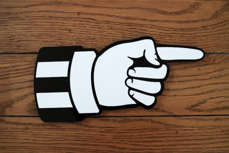 May include: A black and white cartoon hand pointing to the right. The hand is wearing a black and white striped sleeve.