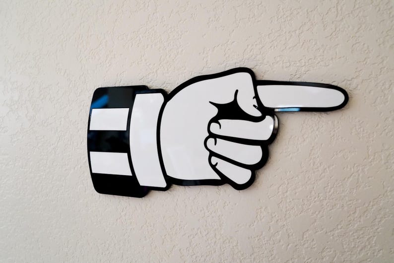 May include: Black and white pointing hand wall decor. The hand is pointing to the right. The hand is stylized and has a simple design.