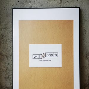 May include: A black picture frame with a white mat and a white card inside. The card has the text "wall ♥ bonito" and the website address "www.wallbonito.com".