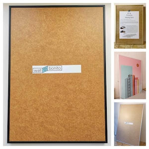 May include: A black framed corkboard with a white label that says "wall &hearts; bonito". The corkboard is brown and has a textured surface.