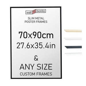 Könnte beinhalten: Ein schwarzer, schmaler Metall-Posterrahmen mit dem Text wall bonito SLIM METAL POSTER FRAMES 70x90cm 27.6x35.4in & ANY SIZE CUSTOM FRAMES. Rechts befinden sich vier kleine horizontale Rahmenprofil-Muster in hellem Holz, Weiß, Schwarz und Silber.