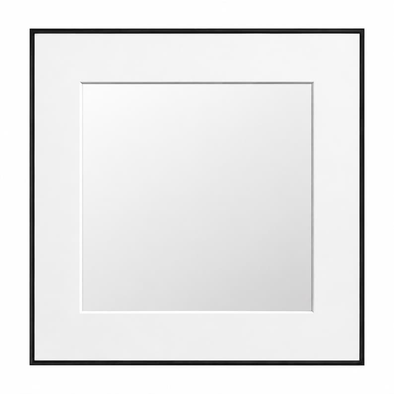 May include: Square black picture frame with a white mat. The frame has a thin black border and a white interior mat, creating a clean, modern aesthetic. The center is a blank white space.