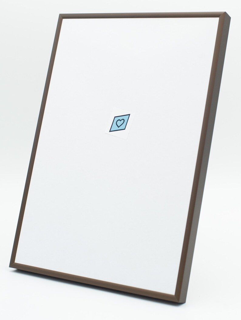 Op de afbeelding: Een bruin fotolijstje met een witte passe-partout en een kleine blauwe hart sticker in het midden.